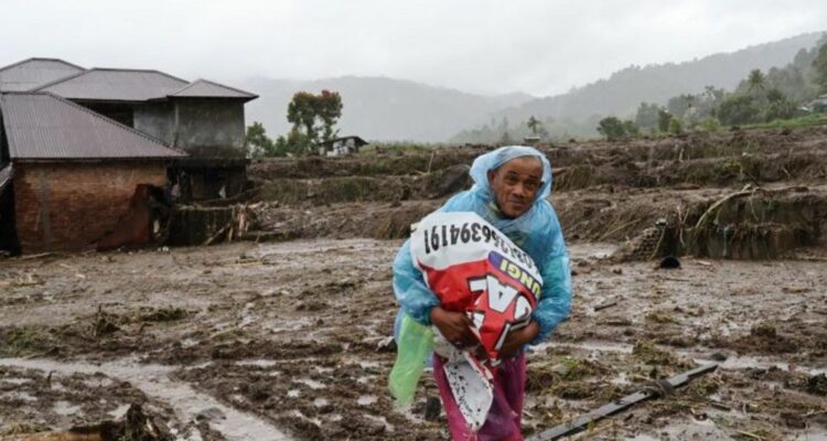 Foto: Seorang warga sedang membawa barang-barang akibat bencana banjir bandang, di Sumatra. Sumber: Istimewa.
